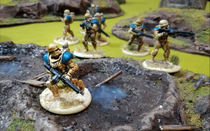 Armored miniature soldiers move across a battle scarred landscape.