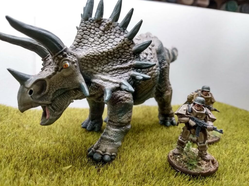 A huge triceratops from Reaper Miniatures moves behind a German powered armored patrol.